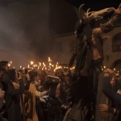 MERCADO MEDIEVAL DE OROPESA - GEATRIPS Zancudo con cabeza de animal rodeado por una multitud con antorchas durante un espectáculo nocturno en el Marcado Medieval de Oropesa